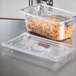 A clear plastic container with food in a Vollrath Super Pan.