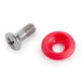 A close-up of a screw and a red plastic circle with a hole.