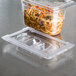 A Vollrath clear polycarbonate lid on a plastic food container filled with noodles and vegetables.