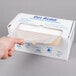 A hand holding a box of Inteplast Group Get Reddi plastic half size bun pan covers on a roll.