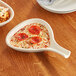 An Acopa ivory stoneware fry pan server with pizza in it on a table.