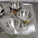 A tray with several Bon Chef Classic Country French Collection green steam table pots with riveted handles.