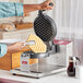 A person making waffles on an Estella Belgian waffle maker with hexagon waffle plates.