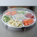 A clear plastic Fineline lid on a tray of vegetables.