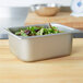 A stainless steel deli pan with salad in it on a counter.