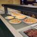 A Hatco built in heated shelf with pizzas and ribs on plates in a hotel buffet.