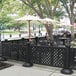 A black fence with tables and white umbrellas on an outdoor patio.