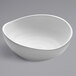 A white oval bowl with a curved edge on a white surface.