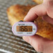 A person using a Taylor purple digital pocket probe thermometer to check the temperature of food.