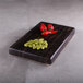 An Elite Global Solutions rectangular faux zebra wood melamine modular riser with beans and red peppers on it.