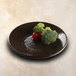 An Elite Global Solutions round melamine plate in aubergine with broccoli and cherry tomatoes on it.