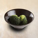 An Elite Global Solutions aubergine-colored melamine bowl filled with broccoli on a table.