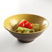 An Elite Global Solutions Pebble Creek olive oil-colored melamine bowl filled with salad with tomatoes and lettuce.