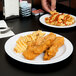 A plate of chicken nuggets and fries on a Thunder Group Nustone white melamine plate on a table.
