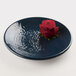 A lapis-colored melamine plate with a red rose with black dots on it.