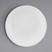 A white Elite Global Solutions Pebble Creek round plate with a white rim on a gray surface.