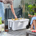 A man and woman putting bottles in a CaterGator outdoor cooler on a patio table.