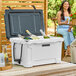 A white CaterGator outdoor cooler on a patio with bottles inside.