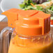 A salad in a plastic container with a Tablecraft orange dressing top on a counter.