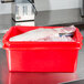 A red Vollrath Traex Color-Mate food storage container on a counter.