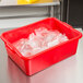 A red Vollrath Traex plastic food storage container on a counter.