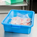 A blue Vollrath Traex food storage container on a counter with fish in it.
