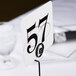 A Cal-Mil iron table card holder with a black and white number on it.
