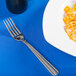 A Oneida Unity stainless steel table fork next to a plate of pasta with cheese.