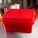 A white Vollrath food storage container with a red lid on a counter.