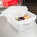 A white Vollrath Traex food storage container with food inside on a counter.
