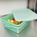 A Vollrath Traex Color-Mate green plastic food storage container with a recessed lid full of limes.