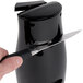A person using a Proctor Silex black electric can opener to sharpen a knife.