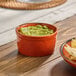 A small orange porcelain ramekin filled with guacamole.