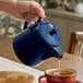 A blue porcelain teapot being used to pour tea into a cup.