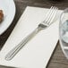 A Oneida Unity stainless steel dinner fork on a white napkin.