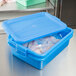 A Vollrath Traex blue plastic food storage container with an open lid.