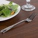 A Oneida Cityscape stainless steel dinner fork on a plate with a salad