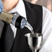 A clear plastic measured liquor pourer with a black collar attached to a bottle, dispensing liquid into a metal jigger.