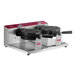 A double waffle maker with two round cooking plates and a stainless steel base.