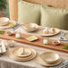 A square beige porcelain butter dish placed on a dining table.