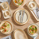 A set of beige porcelain butter dishes displayed with various plates and bowls on a wooden table.