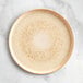 An Acopa Cape beige porcelain plate with brown specks on a white surface.