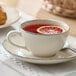 A small round gray porcelain cup filled with tea and garnished with a slice of citrus, placed on a matching saucer.