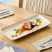 A rectangular gray porcelain platter displayed on a dining table with a plated meal.