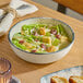 A round gray porcelain bowl filled with salad, featuring lettuce, croutons, and dressing.