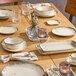 An oval gray porcelain platter displayed on a wooden dining table set with various dinnerware and glassware.