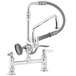 A T&S chrome deck-mounted pre-rinse faucet with two handles and a sprayer.