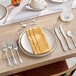 A group of Acopa Edgeworth stainless steel oyster/appetizer/cocktail forks on a table with plates and napkins.
