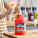 A gallon jug of Carnival King orange snow cone flavoring syrup with a pump dispenser.