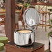A round stainless steel soup induction chafer with a glass top and soft close lid.